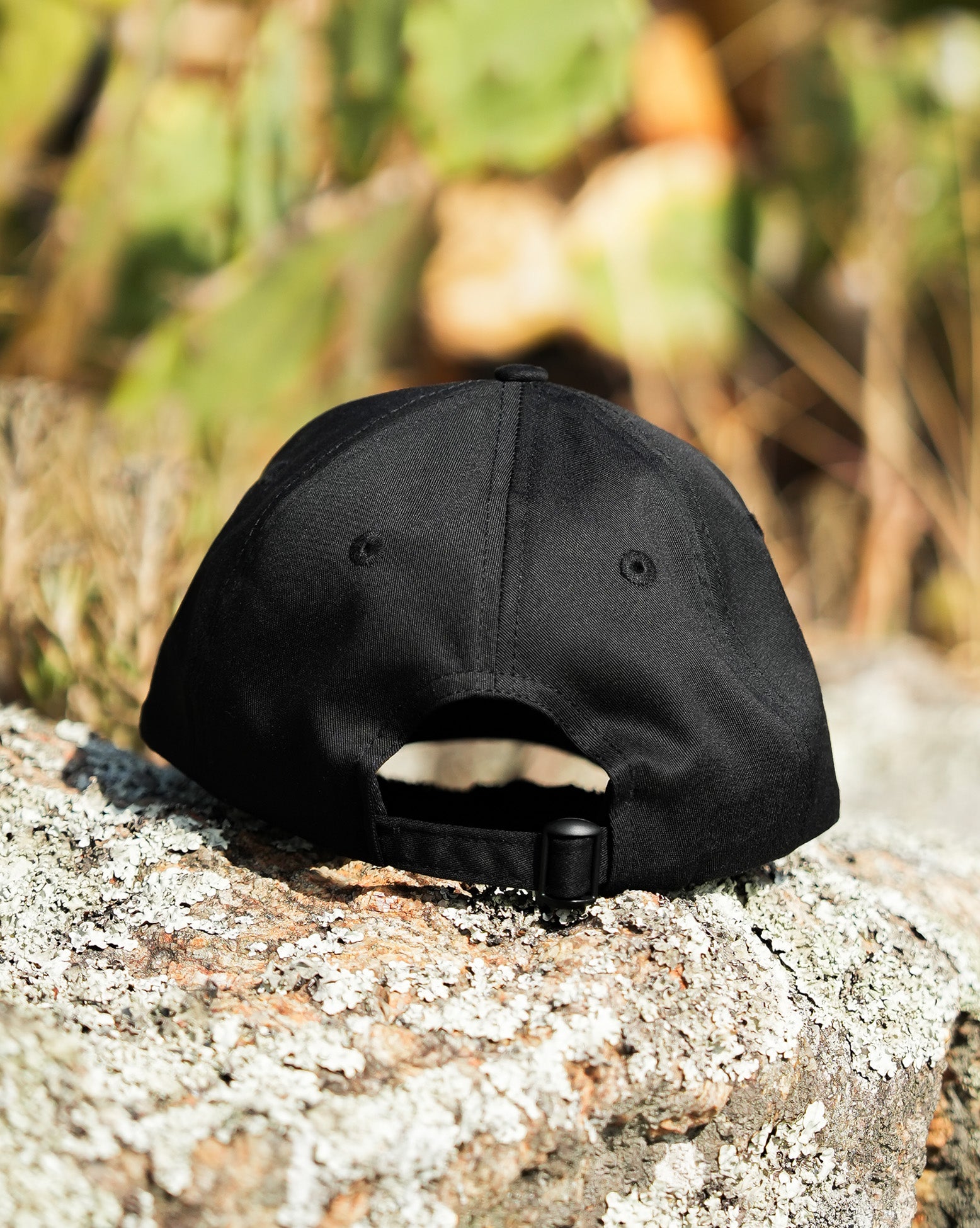 Foto em ambiente natural mostrando a parte de trás do boné Volcom preto, com textura de fundo em tronco de árvore.