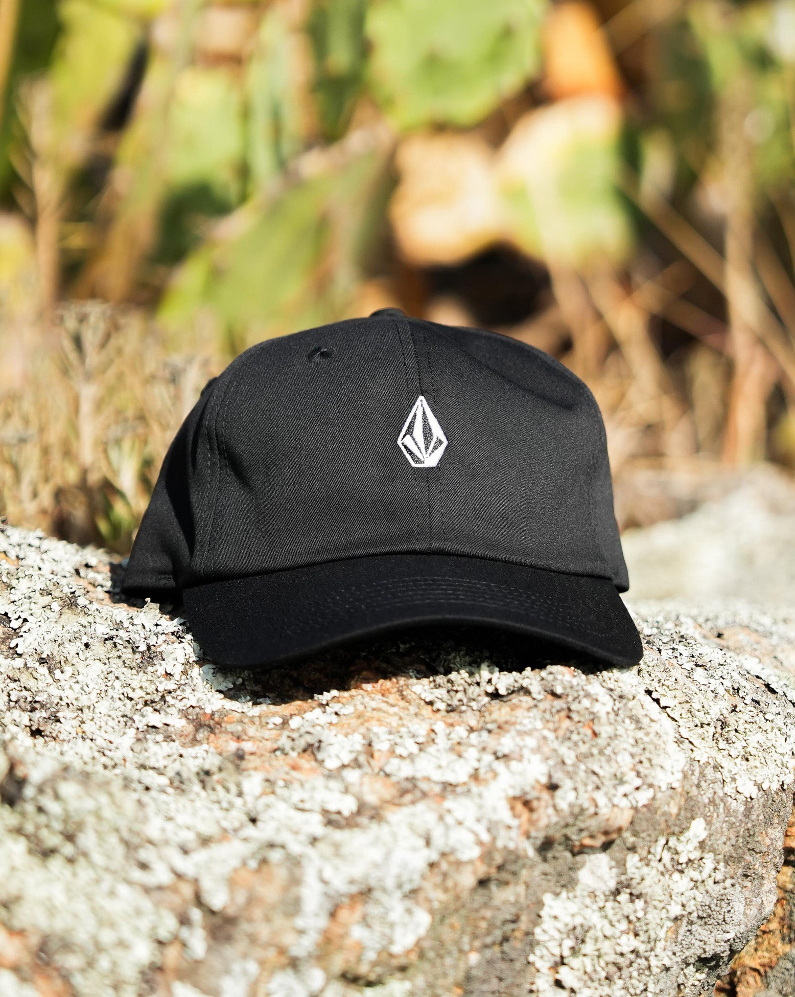 Imagem frontal do boné Volcom preto com logo bordado branco, em ambiente natural, ideal para destacar estilo e autenticidade.