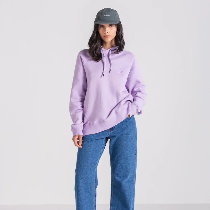 Modelo usando um boné cinza da Volcom, combinado com uma blusa lilás e calça jeans.